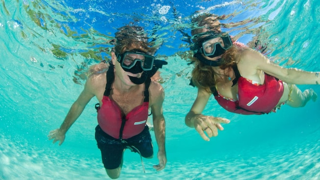 A man and a woman in snorkel gear swimming under the water’s surface A man and a woman in snorkel gear swimming under the water’s surface