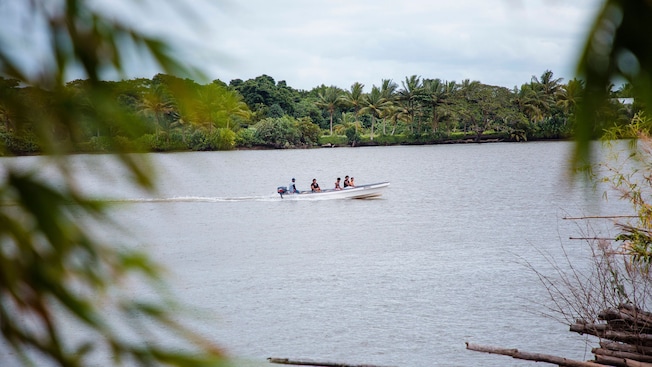 A group of people riding on a long boat along the shores of Suva, Fiji A group of people riding on a long boat along the shores of Suva, Fiji