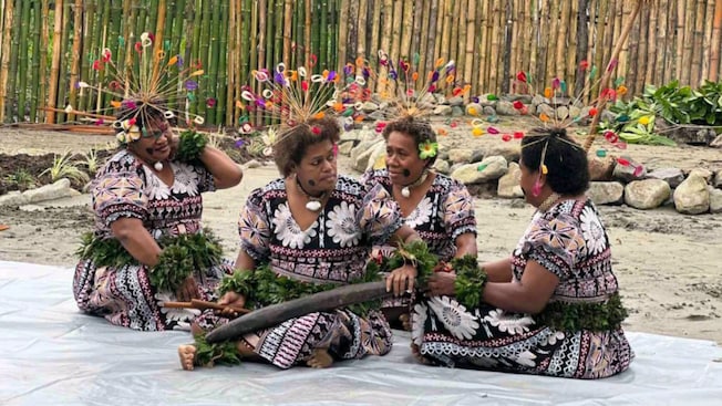Cuatro mujeres de Fiyi con un vestido tradicional y un adorno para la cabeza sentadas en el suelo Cuatro mujeres de Fiyi con un vestido tradicional y un adorno para la cabeza sentadas en el suelo