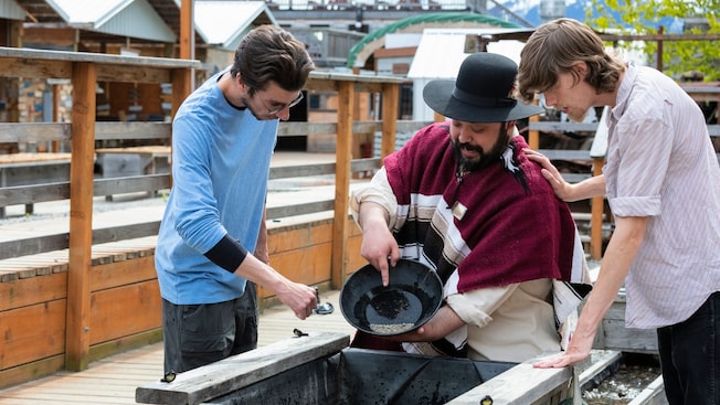 2 young men watching a historic reenactor pan for gold 2 young men watching a historic reenactor pan for gold