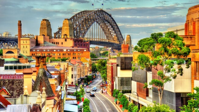 Trees and Victorian era buildings next to the Harbor Bridge in Sydney, Australia