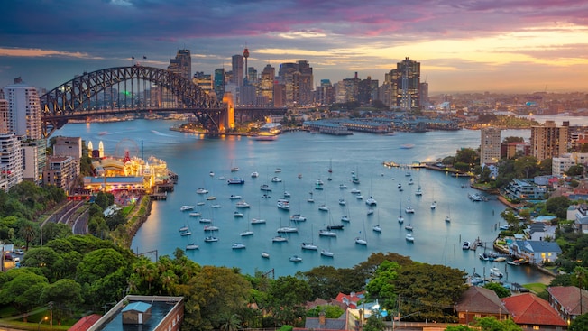 A cityscape of Sydney Harbour with the Sydney Harbour Bridge and sailboats in Sydney, Australia A cityscape of Sydney Harbour with the Sydney Harbour Bridge and sailboats in Sydney, Australia