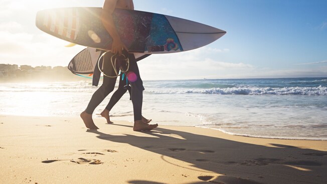 2 surfers carrying their boards into the surf at Bondi Beach in Sydney, Australia