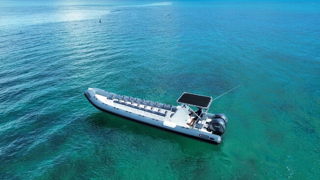 A long, multi passenger power boat on the water