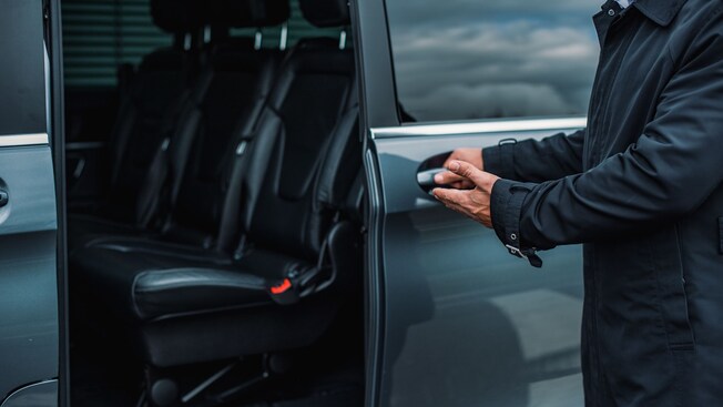 A private driver opening the door of a luxury van