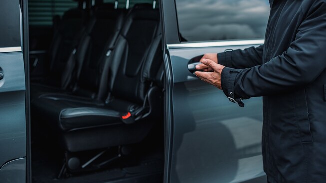A professional driver opening the door of a luxury van