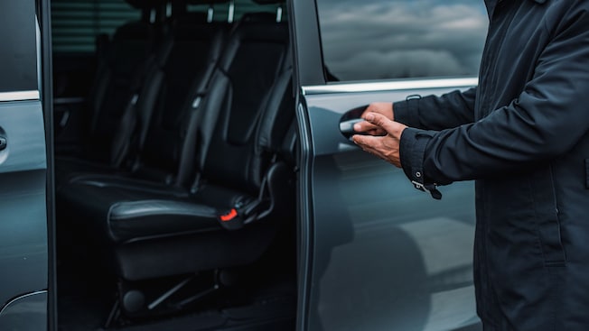 A private driver opening the door of a luxury minivan A private driver opening the door of a luxury minivan