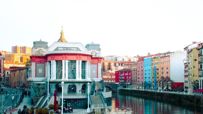 The facade of Erribera Market, a historic riverside market with large windows and a central dome in Bilbao, Spain