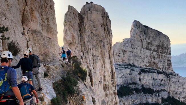 Visitantes usando una cuerda guía para caminar por un sendero empinado en el acantilado