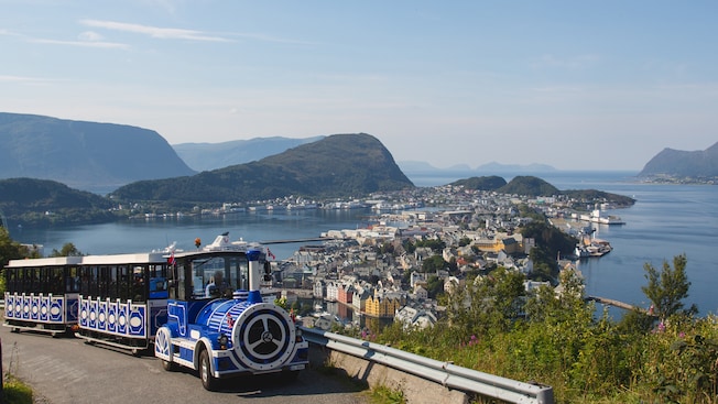 The Ålesund City Train driving up a hill with a panoramic view of Ålesund in the background The Ålesund City Train driving up a hill with a panoramic view of Ålesund in the background