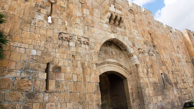 A historic stone gate with an arched entrance and fortified walls featuring decorative carvings