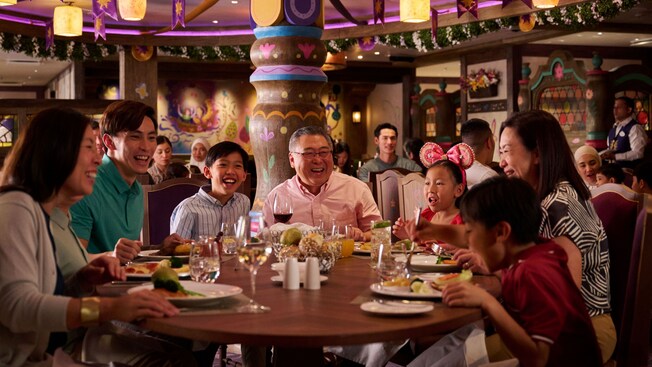 A large family dining around a circular table at Enchanted Summer Restaurant on the Disney Adventure cruise ship