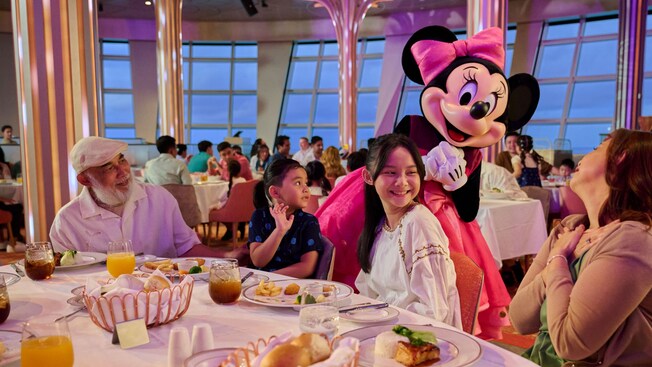 Minnie Mouse greeting Guests seated at a table in Hollywood Spotlight Club on the Disney Adventure cruise ship