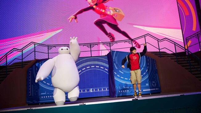 The Baymax Super Exercise Expo, with Baymax and a Cast Member standing together on stage