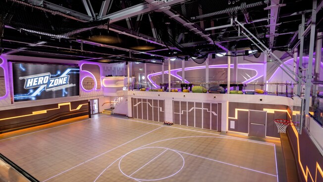 An upscale indoor basketball court and the words ‘Hero Zone’ projected on a large screen
