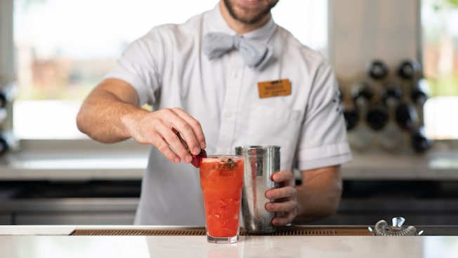 A Cast Member prepares a glass of refreshing Strawberry Basil Lemonade