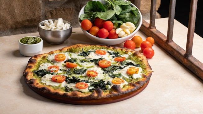 A wood-fired pizza with cherry tomatoes, mozzarella and greens