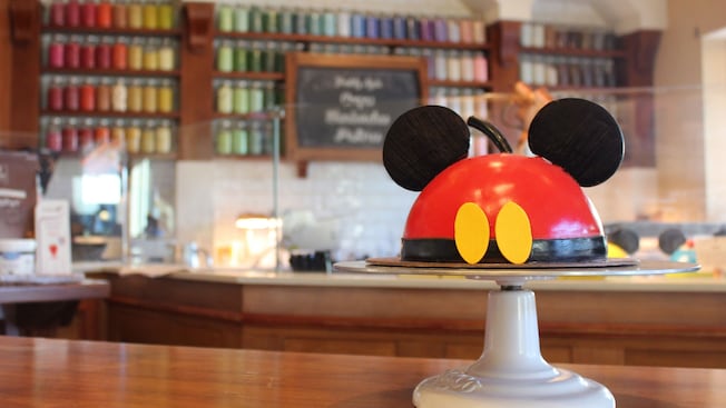 A Mickey Mouse dome cake atop a cake plate in Amorette's Patisserie at Disney Springs