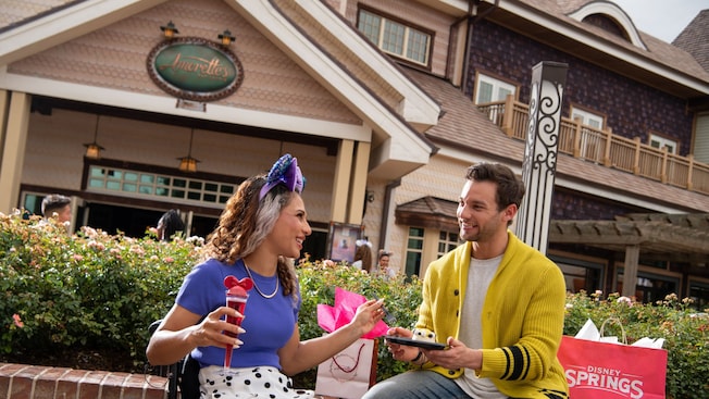 A young couple enjoys cake and sparkling wine outside Amorette’s Patisserie at Disney Springs