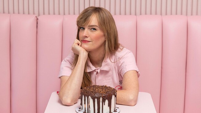 Erin McKenna sentada en una mesa con un pastel