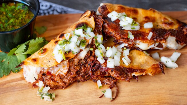 Beef birria tacos topped with an onion cilantro salsa