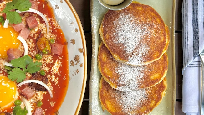 A brunch serving from Frontera Cocina featuring chilaquiles, Huevos Motuleños, pancakes and a mimosa