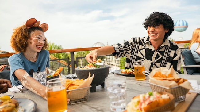 Two Guests enjoying food and beverages while sitting on an outdoor deck at Paddlefish	