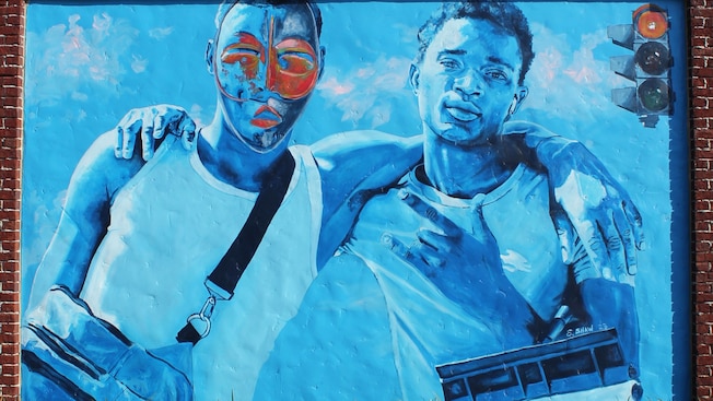 A mural along a pathway featuring 2 boys arm in arm