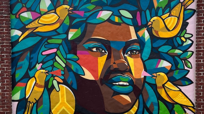 A mural of a woman’s face surrounded by 4 birds