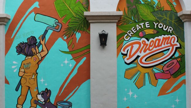 A mural of a puppy watching a girl painting