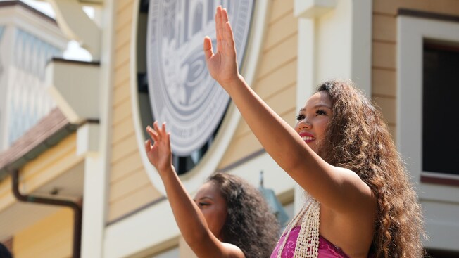Dos bailarines de hula con conjuntos florales que actúan al aire libre en Disney Springs
