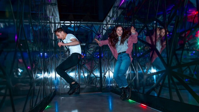 Two Guests jumping into the air in a mirrored room with lights on the floor