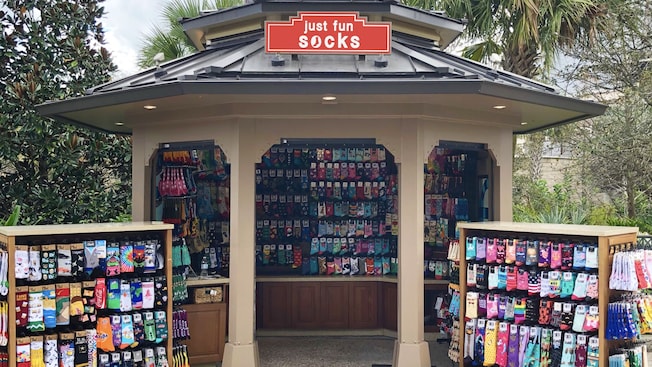 An outdoor gazebo and 2 nearby shelves filled with colorful socks