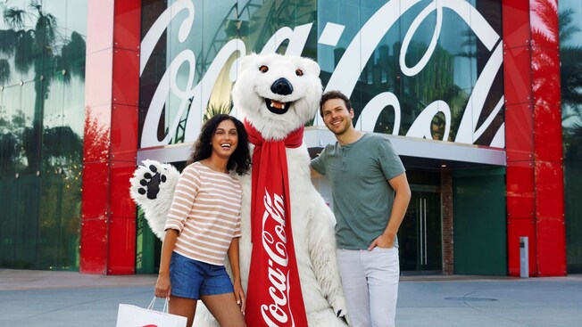 Two Guests posing for a photo with a Coca Cola polar bear while standing outside of the Coca Cola Store
