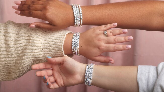 Tres manos adornadas con brazaletes de la amistad 