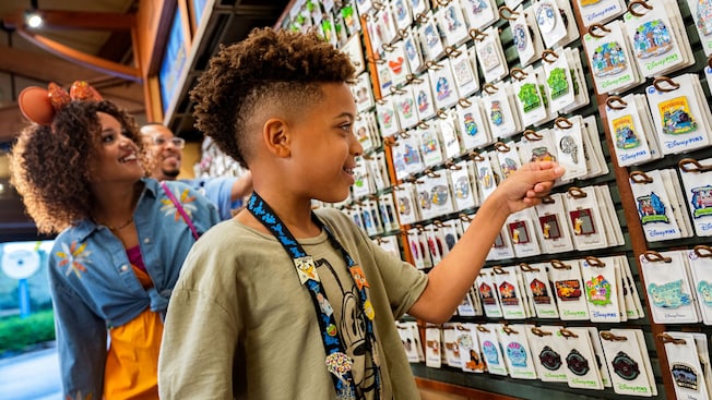 A boy picking a pin from a pegboard next to his parents