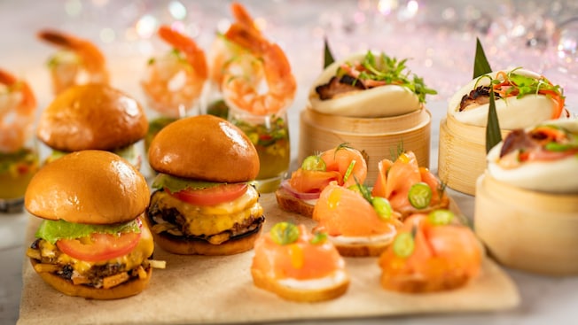 A platter of miniature Beef Sliders, Smoked Salmon Tartines, Poached Shrimp in Pineapple Jalapeno Aguachile and Cha Sui Bao Buns