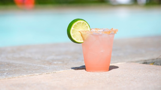 A margarita served with lime near a pool