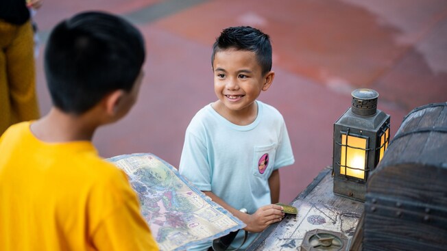 Dos jóvenes Visitantes participando en el desafío Treasures of the Seven Seas en Magic Kingdom Park