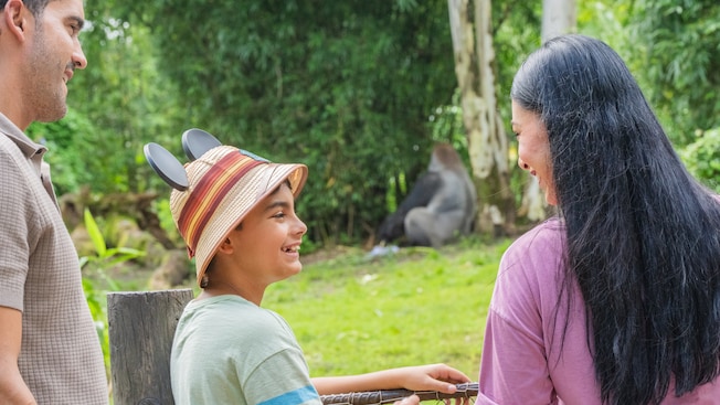 A family of 3 watching a resting gorilla in Gorilla Falls Exploration Trail at Disney’s Animal Kingdom theme park