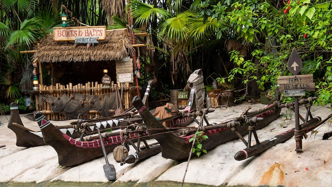 Canoes on a beach near a shack with a sign that says ‘Boats and Baits’