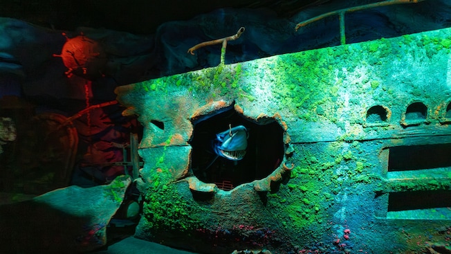 Chum the shark poking out of a hole in a sunken ship at The Seas with Nemo & Friends