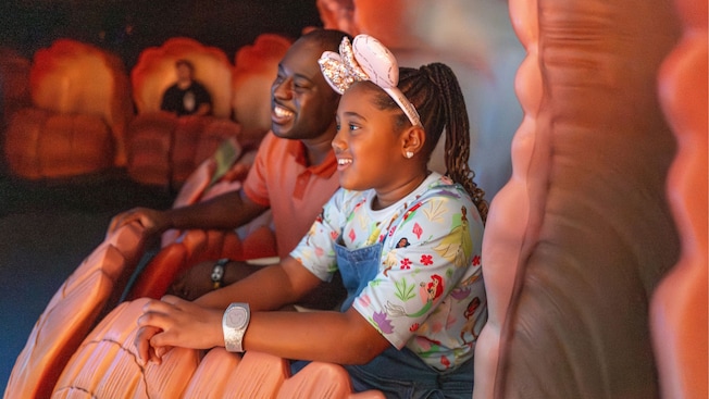 A father and daughter riding in a seashell at The Seas with Nemo & Friends