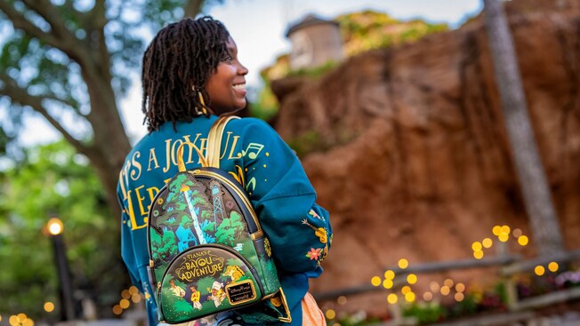 A woman with her back turned, wearing a Tiana’s Bayou Adventure Loungefly Mini Backpack and a jersey