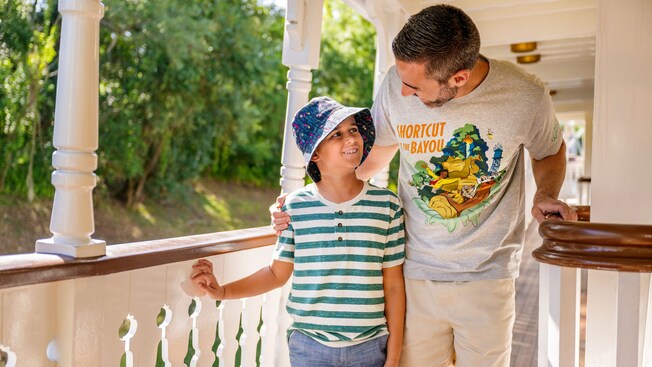 Father and son smiling at each other while wearing Tiana’s Bayou Adventure merchandise