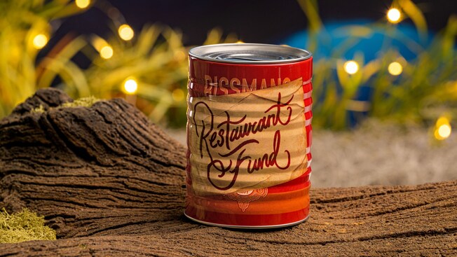 A can labeled ‘Restaurant Fund’ sitting on a log
