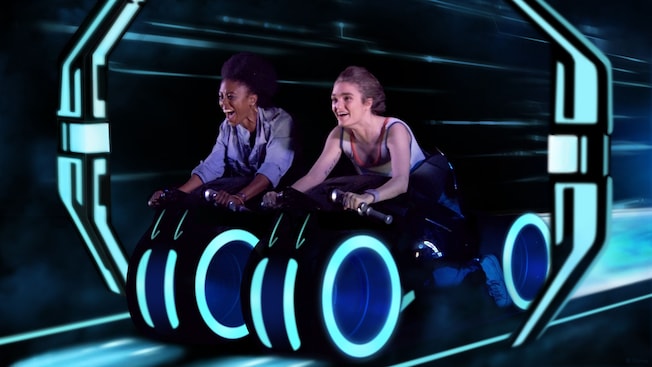 2 Visitantes a bordo de vehículos en la atracción TRON Lightcycle Run en el Parque Temático Magic Kingdom