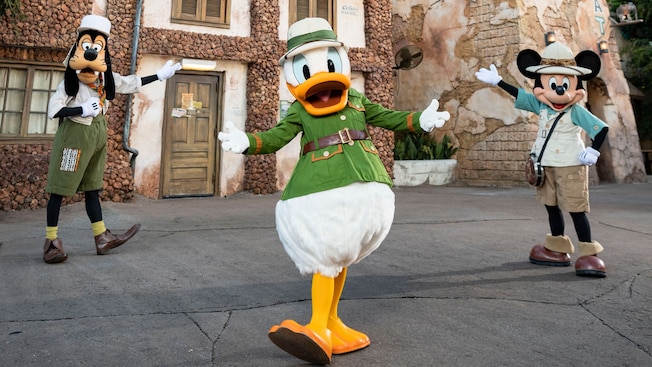 Mickey Mouse, Donald Duck e Goofy em trajes de safári em frente ao Tusker House Restaurant