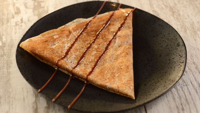 Um crepe noisette com calda de chocolate por cima, servido em um prato