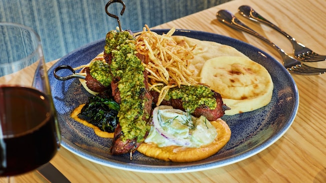 Un apetitoso plato de brochetas de ternera a la parrilla con hummus, pan pita e ingredientes mediterráneos